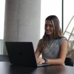 Young woman using a laptop in a modern indoor setting, focused on online study.