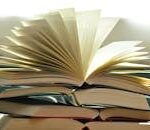 A close-up of a stack of open books with pages fanned out, capturing a study atmosphere.