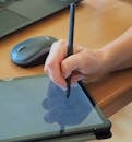 Close-up of a hand using a capacitive stylus on a tablet screen, showcasing modern technology.